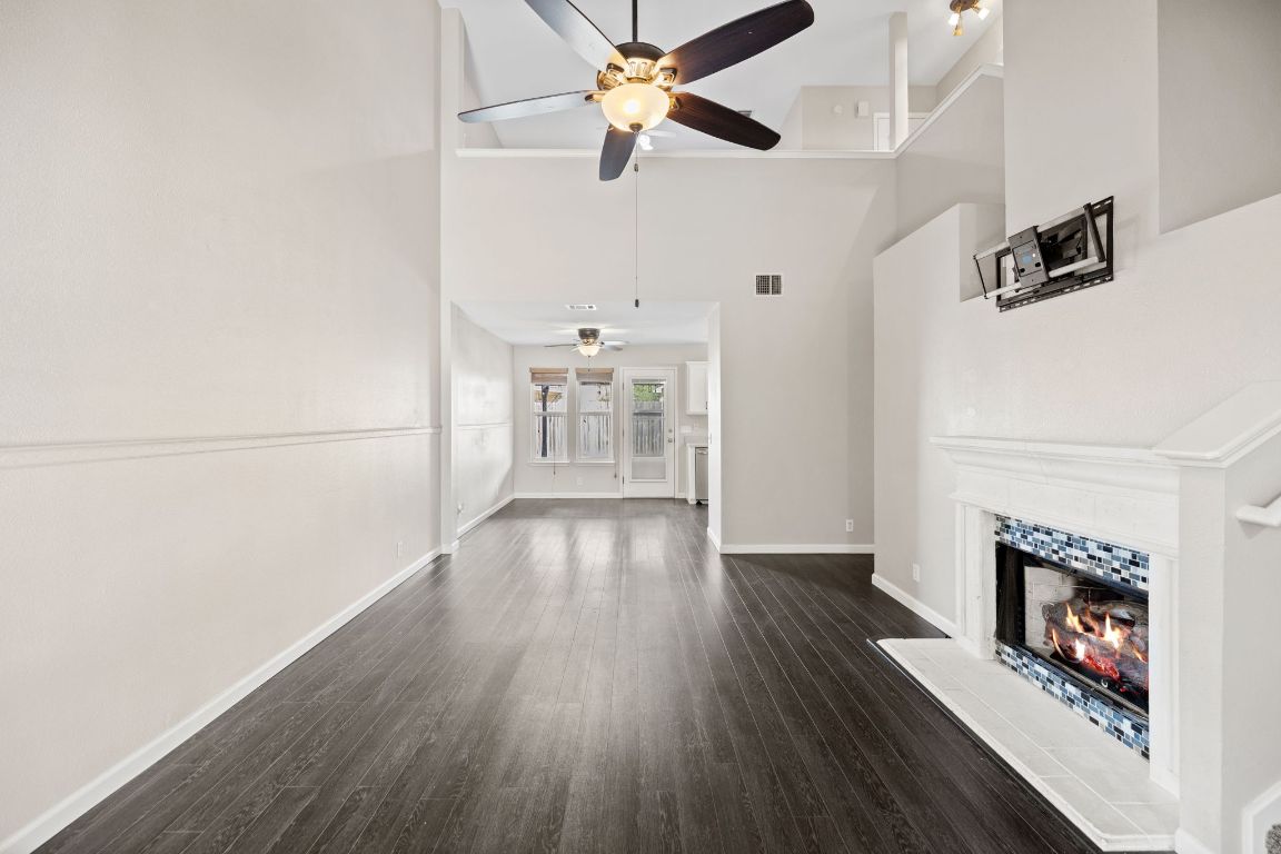 413 Clarks Way Hutto, TX 78634 - Photo 3 of 34 living room featuring a towering ceiling, a fireplace, dark wood-type flooring, and ceiling fan