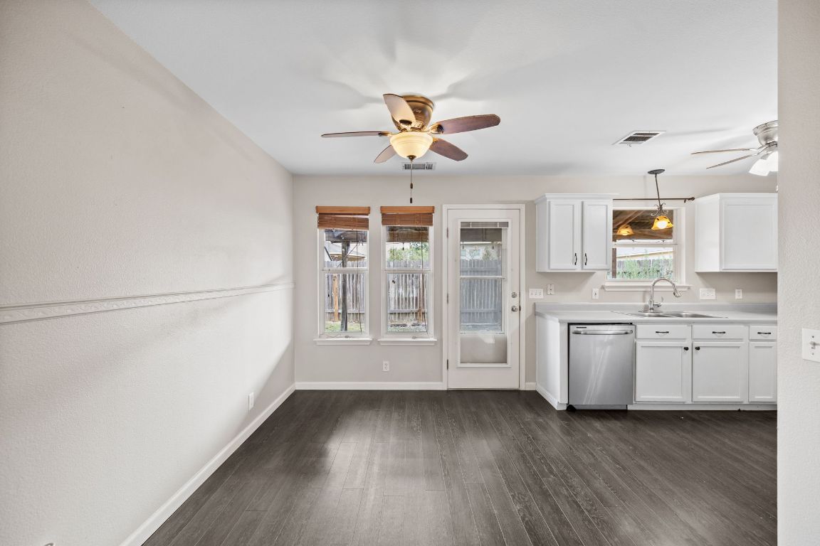 413 Clarks Way Hutto, TX 78634 - Photo 7 of 34 Kitchen with white cabinetry, hanging light fixtures, dark wood-style floors, dishwasher, and light countertops