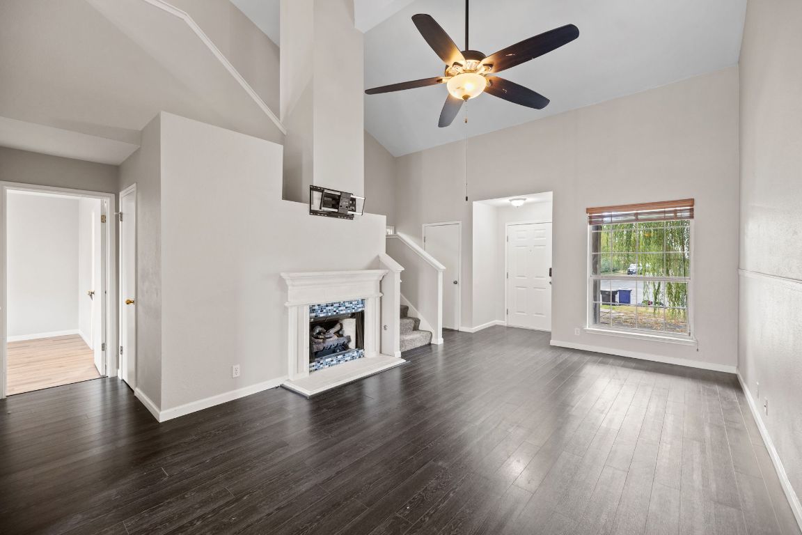 413 Clarks Way Hutto, TX 78634 - Photo 8 of 34 Unfurnished living room featuring stairway, high vaulted ceiling, dark wood-style flooring, and ceiling fan