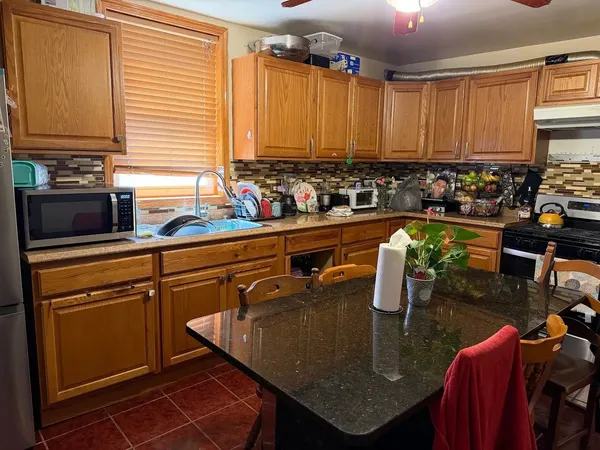 a kitchen with stainless steel appliances granite countertop a sink a table and chairs in it