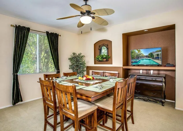 a dining room with furniture a flat screen tv and a large window