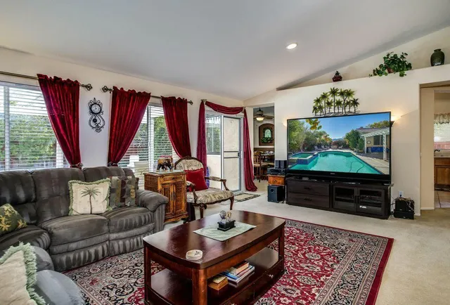 a living room with furniture a flat screen tv and a large window