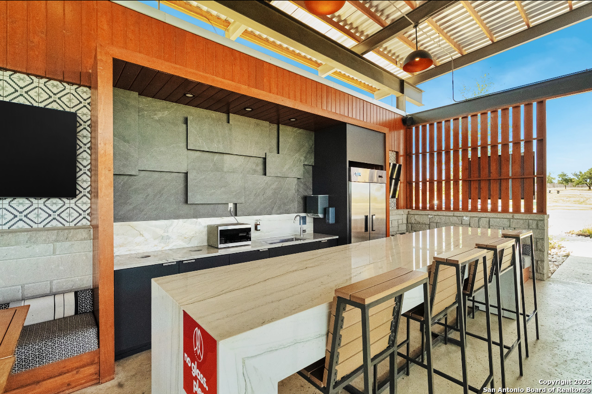 5386 Ranch Road 1376, Unit 232 Fredericksburg, TX 78624 - Photo 10 of 13 a kitchen with stainless steel appliances kitchen island granite countertop a table chairs in it and wooden floor