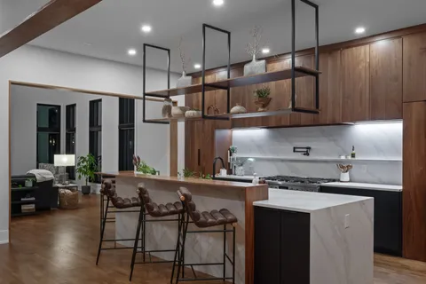 a kitchen with stainless steel appliances granite countertop a stove a sink a refrigerator and chairs