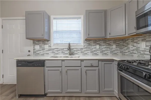 a kitchen with granite countertop a sink cabinets and stainless steel appliances