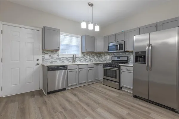 a kitchen with stainless steel appliances kitchen island granite countertop a stove a sink dishwasher a refrigerator and a refrigerator with wooden floor