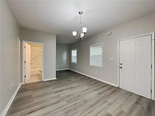 an empty room with wooden floor cabinet and windows