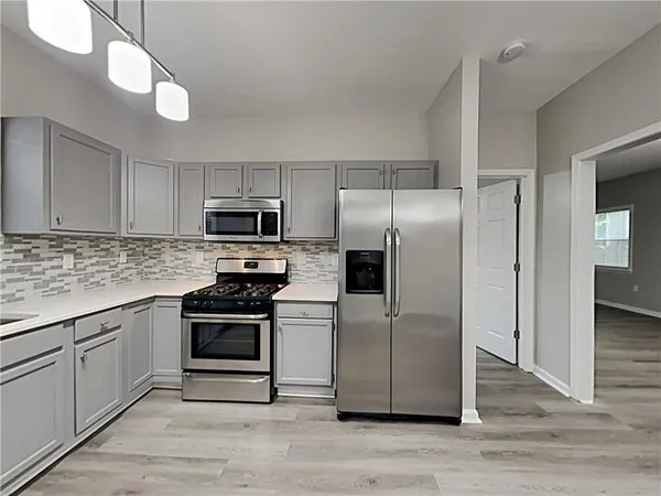 a kitchen with granite countertop a refrigerator and a stove top oven