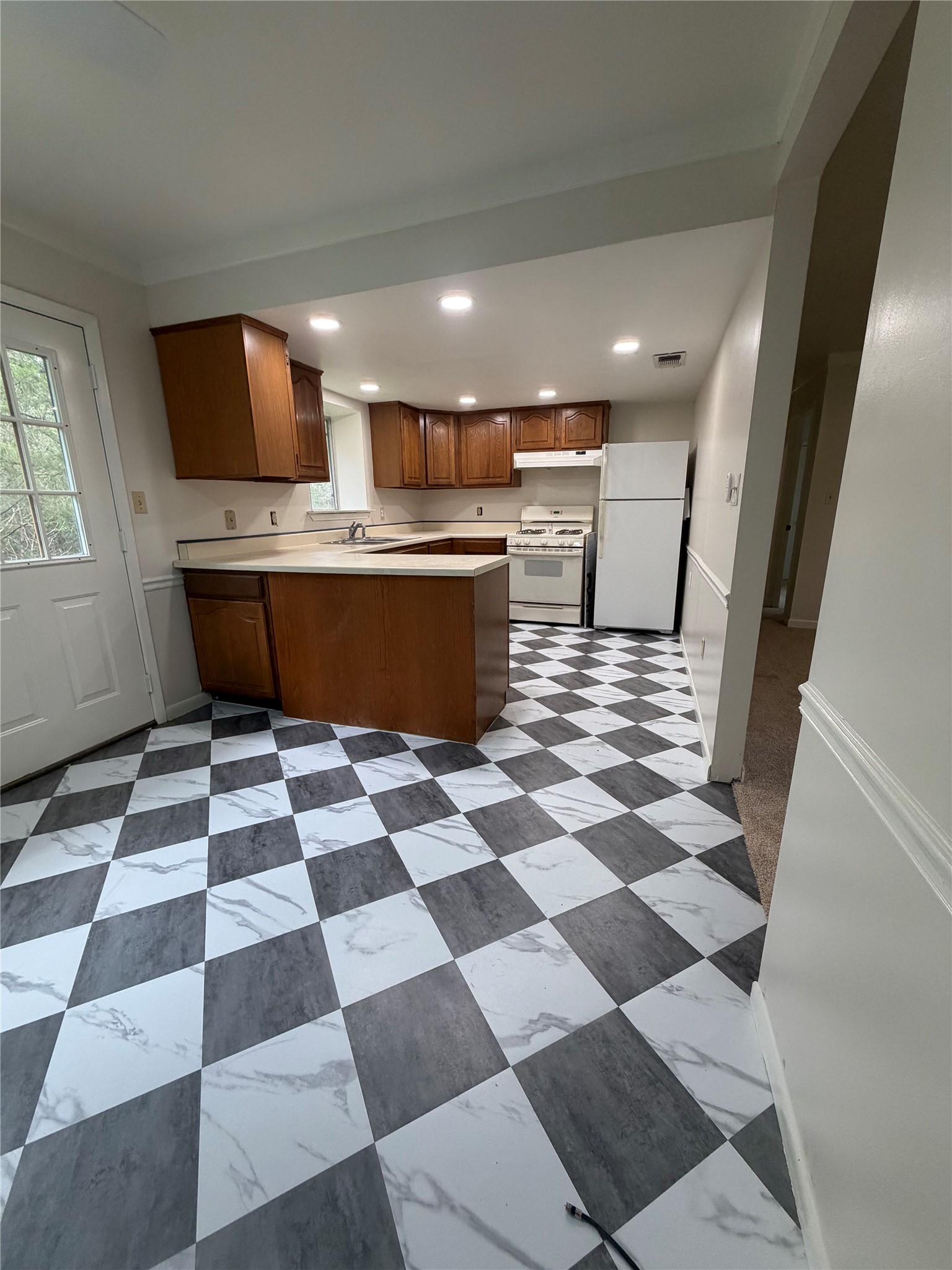 214 The Forest Road Dale, TX 78616 - Photo 6 of 18 A well-lit kitchen with classic checkered flooring, ample cabinetry, and functional appliances.