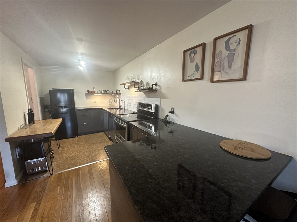 121 Tremont Street, Unit 114 Boston, MA 02135 - Photo 11 of 13 a living room with furniture and a wooden floor
