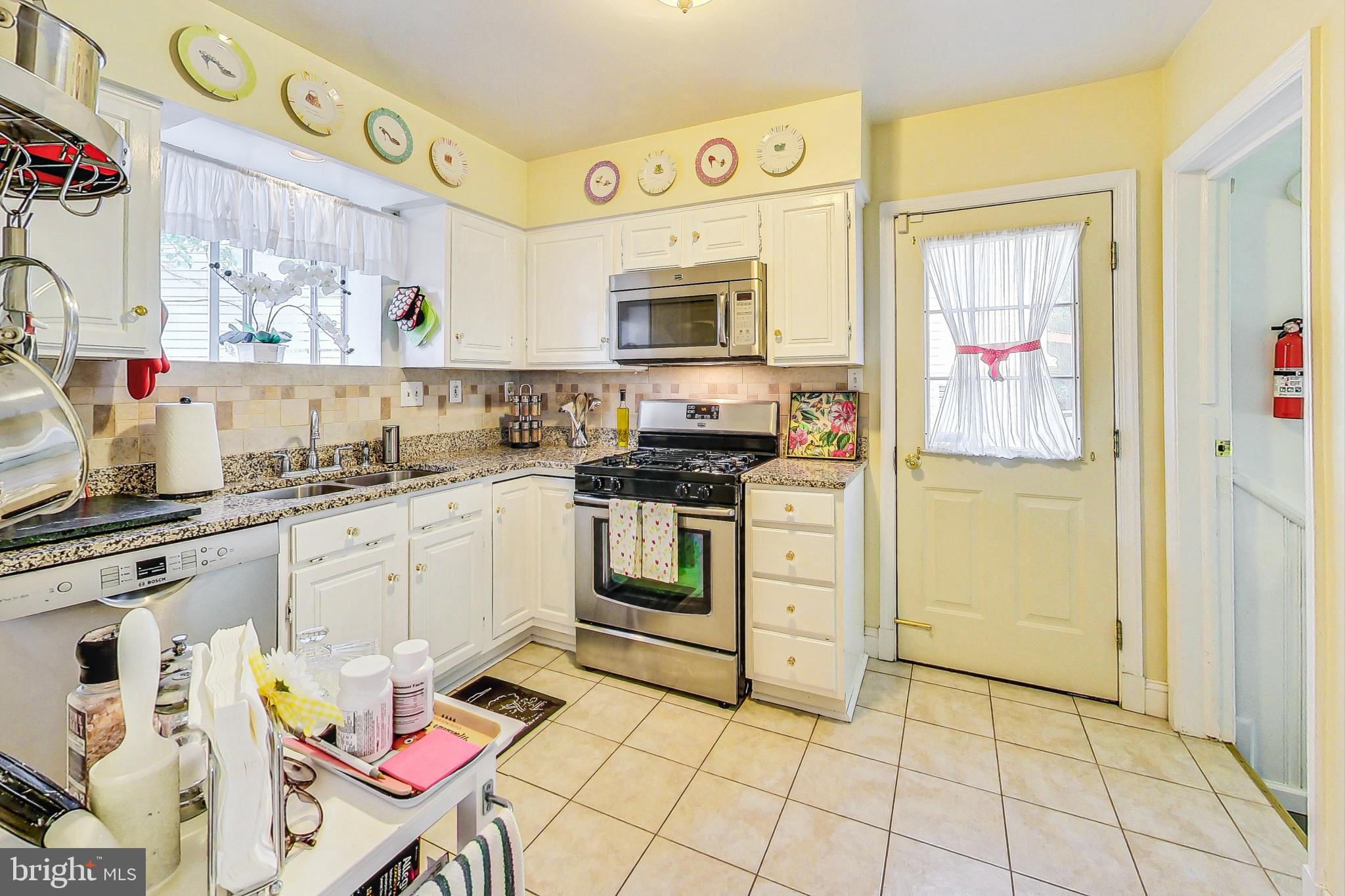 10404 Grandin Road Silver Spring, MD 20902 - Photo 10 of 38 a kitchen with stainless steel appliances a stove a sink and a refrigerator with white cabinets