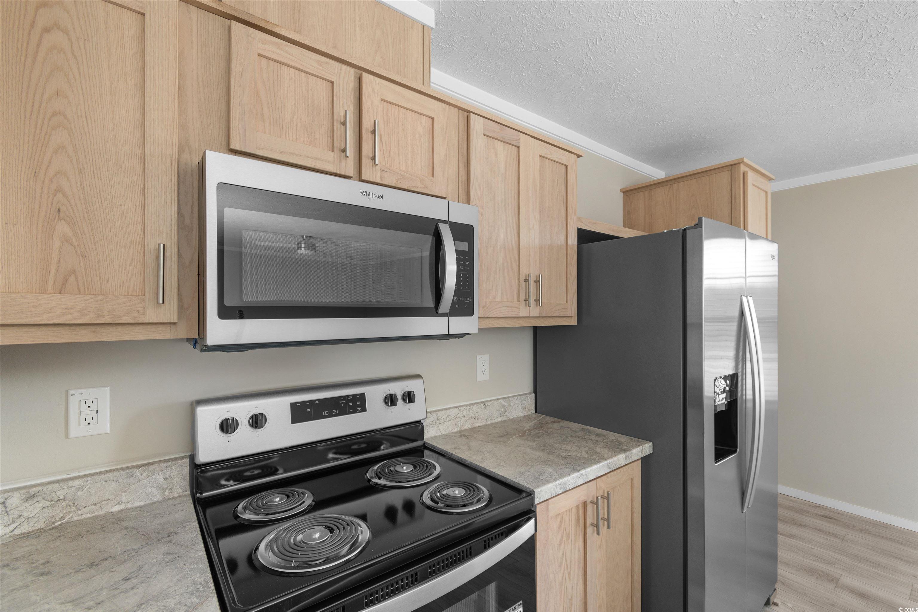 121 Feather Drive Georgetown, SC 29440 - Photo 14 of 40 Kitchen featuring appliances with stainless steel finishes, light countertops, light brown cabinetry, a textured ceiling, and light wood-type flooring