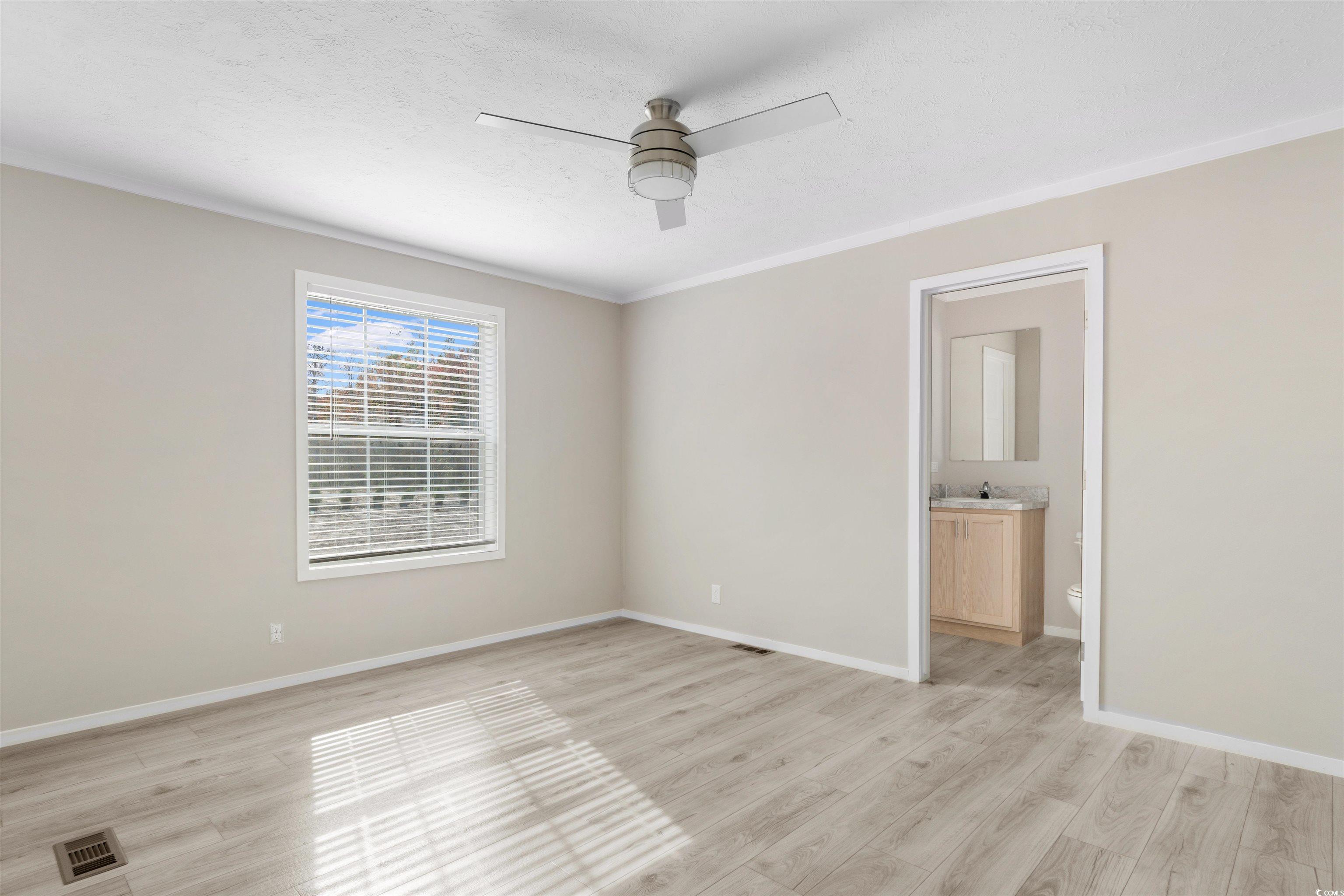 121 Feather Drive Georgetown, SC 29440 - Photo 17 of 40 Unfurnished bedroom featuring ceiling fan, light wood-style flooring, connected bathroom, crown molding, and a textured ceiling