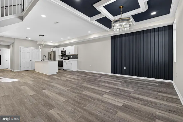 a view of an empty room with kitchen and a window