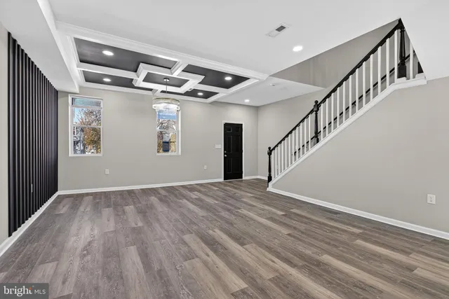 a view of an empty room with wooden floor and stairs