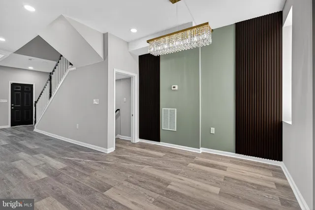 a view of an empty room with wooden floor and a bathroom
