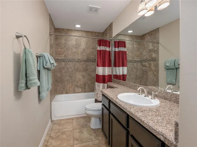 a bathroom with a granite countertop sink a toilet and shower