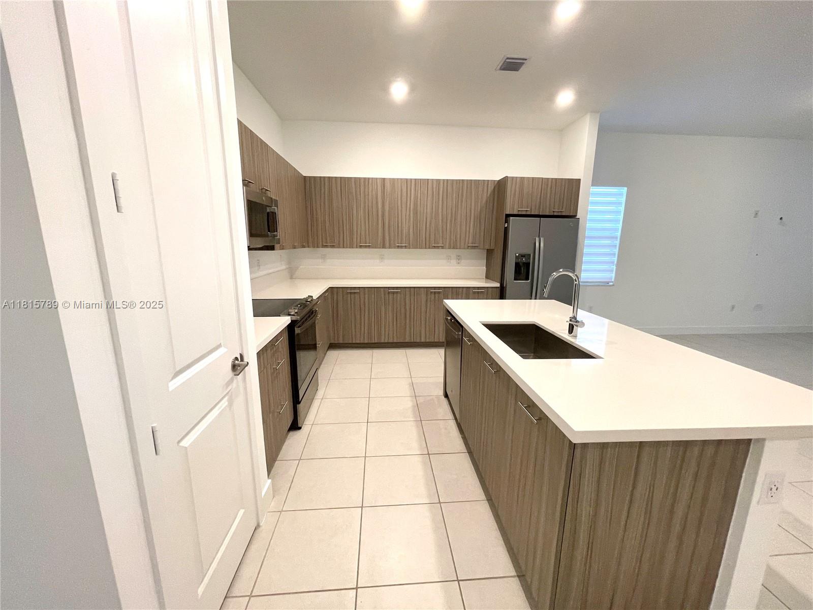 4506 Southwest 174th Avenue, Unit 4506 Miramar, FL 33029 - Photo 53 of 80 a kitchen with a sink a stove top oven a sink and a refrigerator