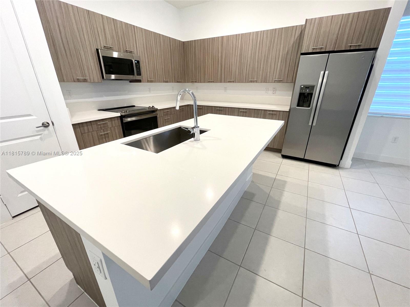4506 Southwest 174th Avenue, Unit 4506 Miramar, FL 33029 - Photo 62 of 80 a kitchen with stainless steel appliances a sink a stove a microwave a counter top space and cabinets