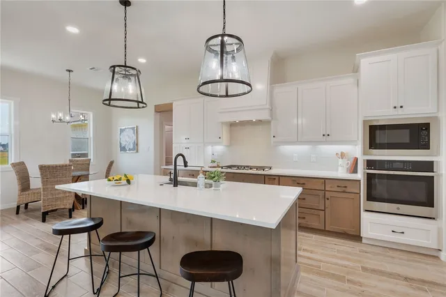 a kitchen with stainless steel appliances a sink a stove a table and chairs