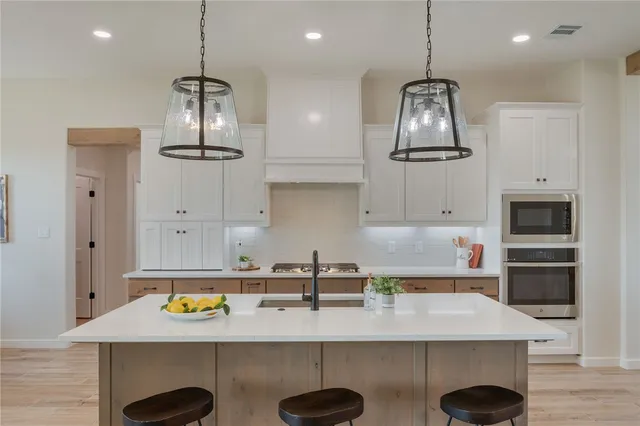 a kitchen with stainless steel appliances granite countertop a sink a stove and a wooden floors