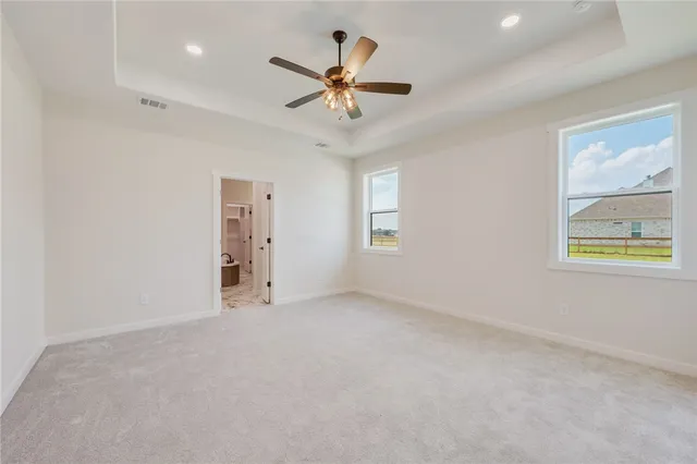 an empty room with ceiling fan and windows