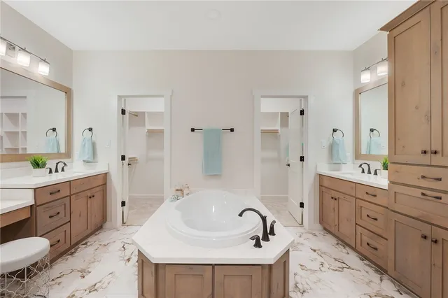 a bathroom with a double vanity sink mirror and bathtub