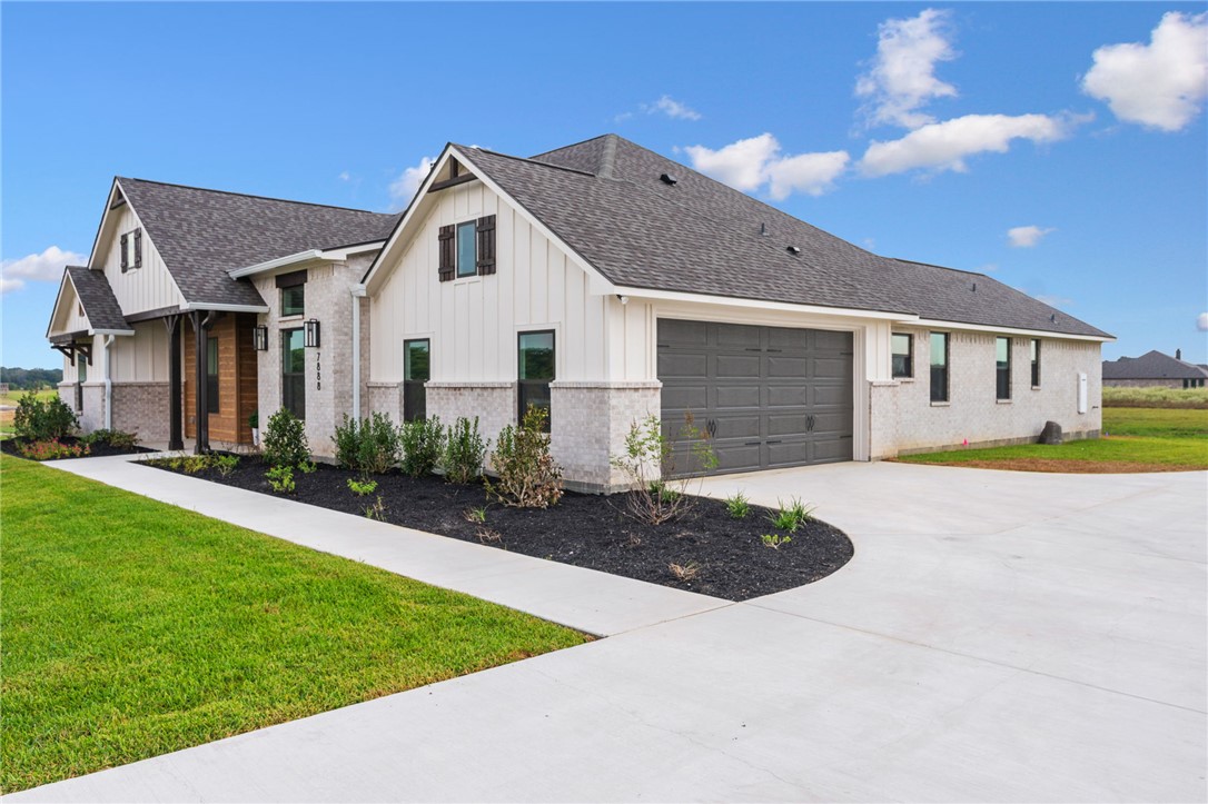 7888 Mathis Crk Drive Bryan, TX 77808 - Photo 2 of 41 View of side of property featuring a lawn, board and batten siding, a shingled roof, concrete driveway, and brick siding