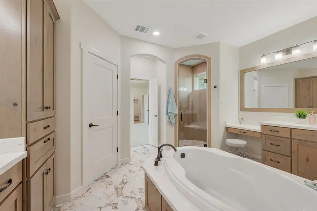 a spacious bathroom with a tub sink and mirror