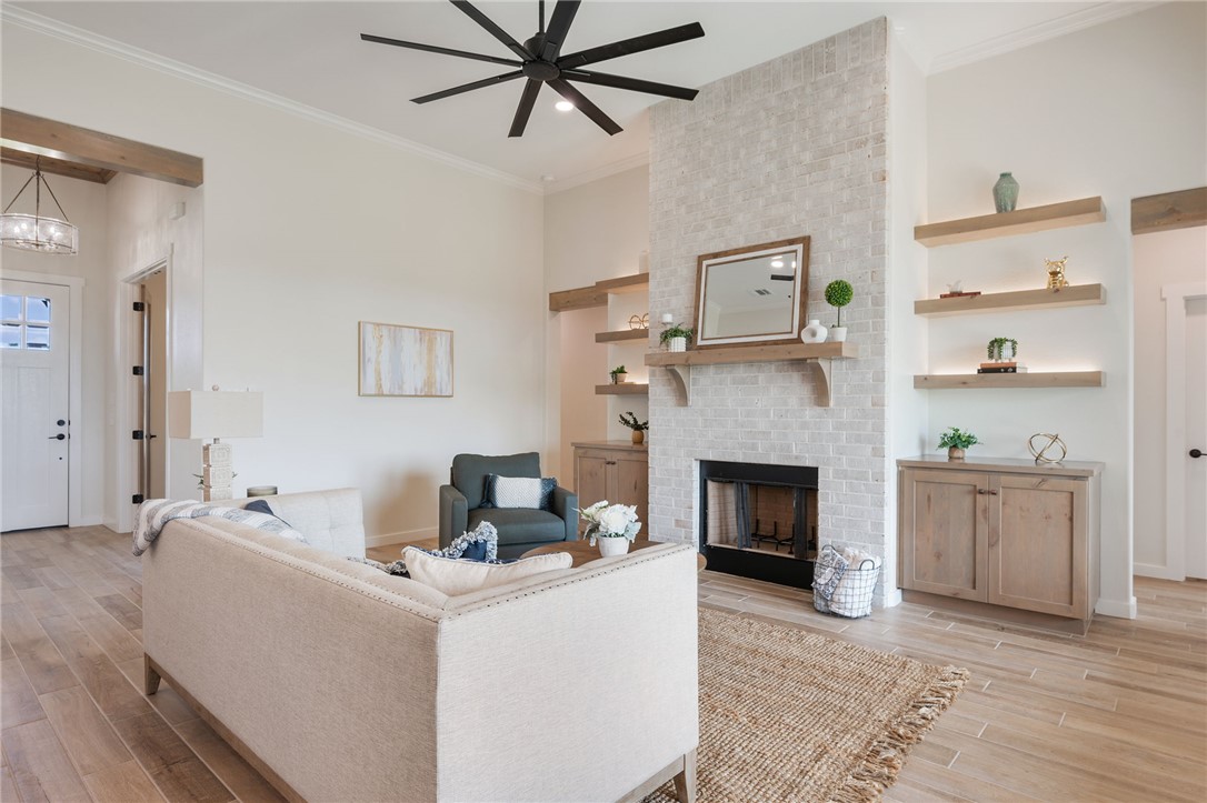 7888 Mathis Crk Drive Bryan, TX 77808 - Photo 8 of 41 Living area with light wood-style floors, a brick fireplace, ornamental molding, and a ceiling fan