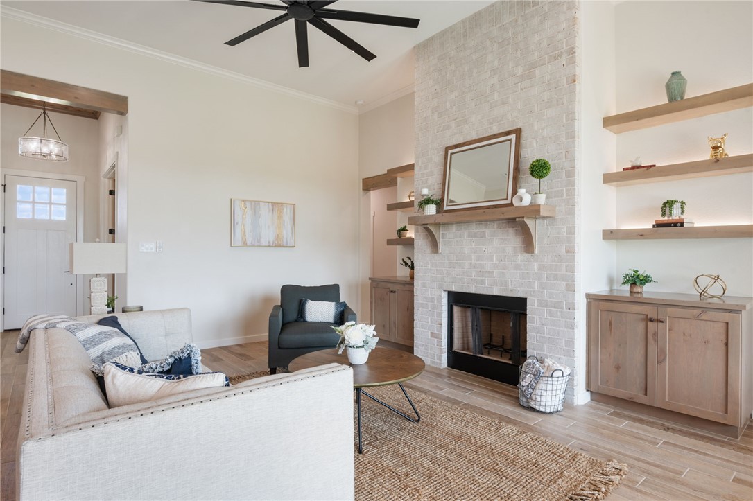 7888 Mathis Crk Drive Bryan, TX 77808 - Photo 9 of 41 Living area with light wood-style flooring, a brick fireplace, ornamental molding, and ceiling fan