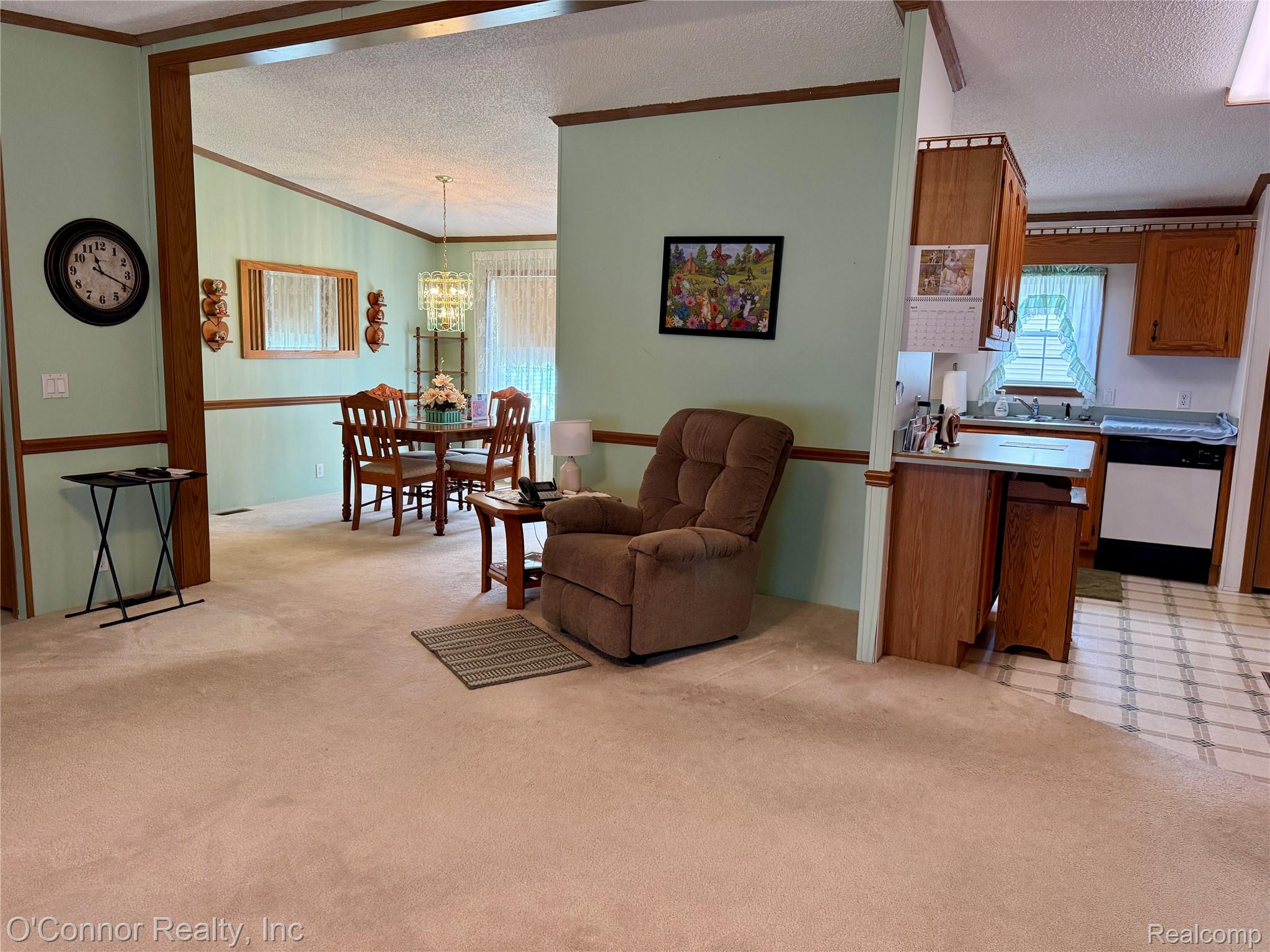 3333 Ravenswood Road, Unit 61 Marysville, MI 48040 - Photo 4 of 18 Living room with ornamental molding, light colored carpet, a textured ceiling, and a chandelier