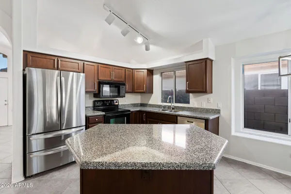 a kitchen with granite countertop a refrigerator a sink a stove a microwave and island