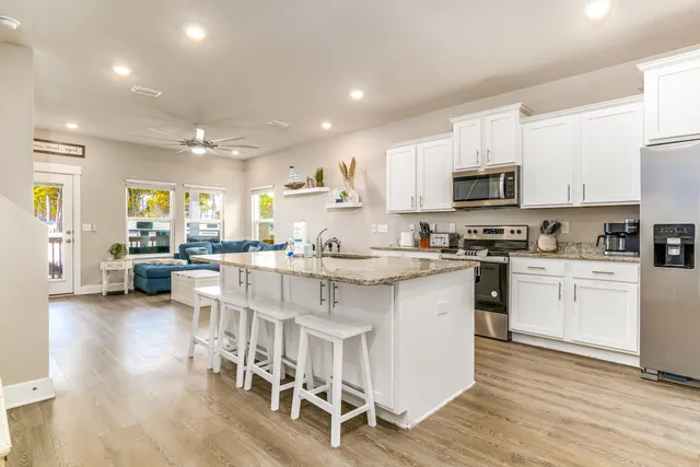 a kitchen with stainless steel appliances granite countertop a stove top oven a sink dishwasher a dining table and chairs with wooden floor