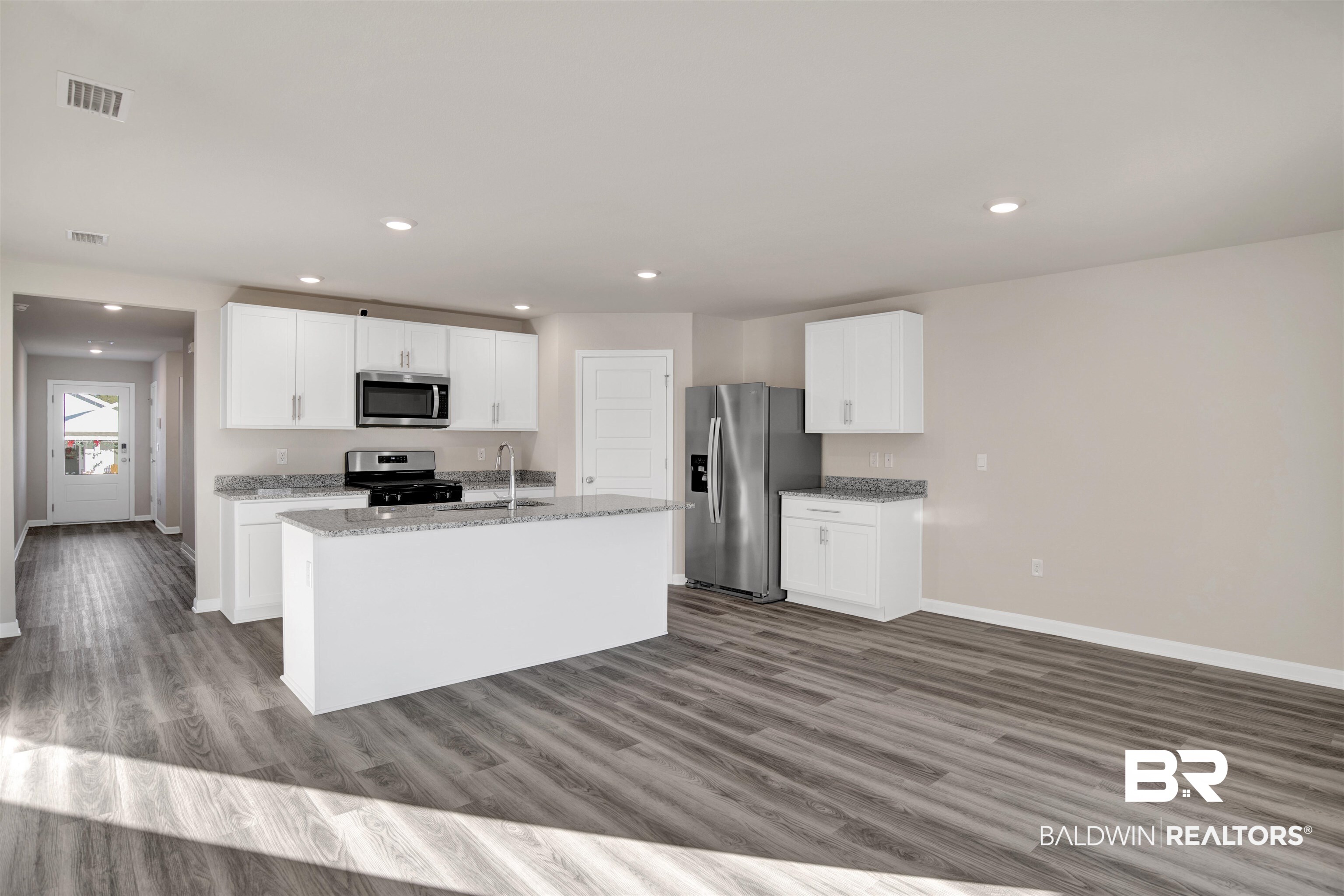 32038 Lyon Road Daphne, AL 36527 - Photo 24 of 30 Kitchen with white cabinets, appliances with stainless steel finishes, light stone countertops, recessed lighting, and a kitchen island with sink