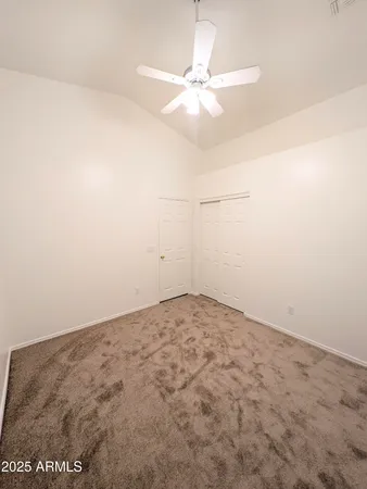 an empty room with a fan & a window