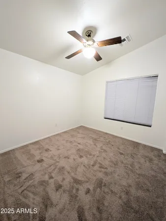 an empty room with a window and a fan