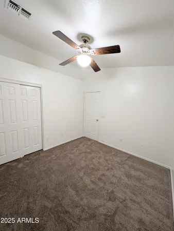 an empty room with windows and fan