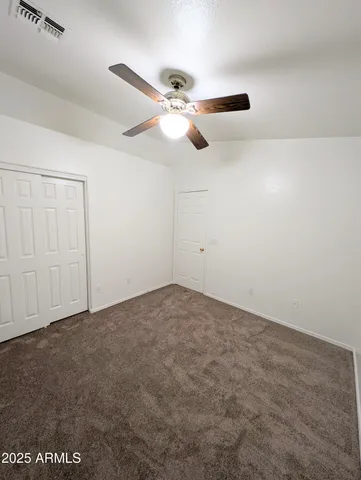 an empty room with windows and fan