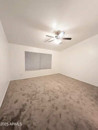 an empty room with a chandelier fan and windows