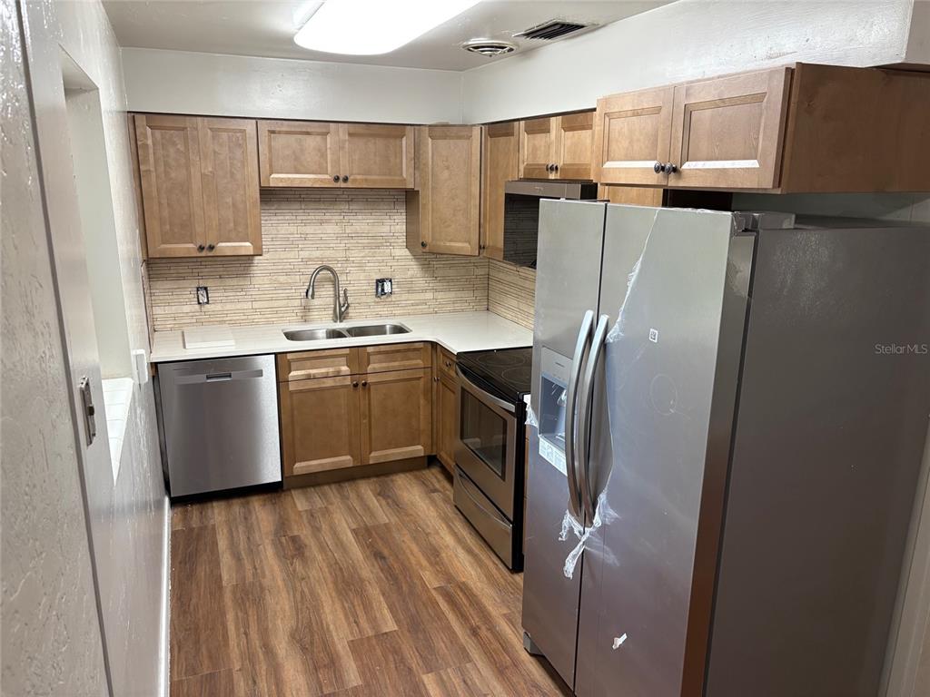 401 Northwest 36th Street Gainesville, FL 32607 - Photo 3 of 13 a kitchen with stainless steel appliances granite countertop a refrigerator a sink dishwasher a stove and white countertops with wooden floor