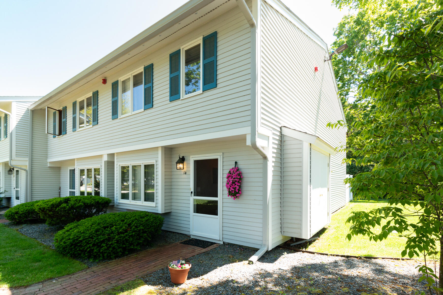174 Lowell Road, Unit U14 Mashpee, MA 02649 - Photo 2 of 31 a view of a white house with a small yard and a large tree