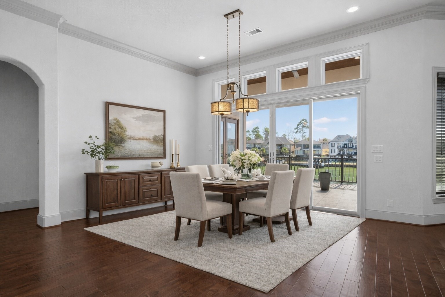 12349 Tramonto Conroe, TX 77304 - Photo 13 of 50 This elegant dining room features hardwood floors, a modern chandelier, and large windows offering abundant natural light and views of a spacious patio and greenery. The space is airy and perfect for entertaining.