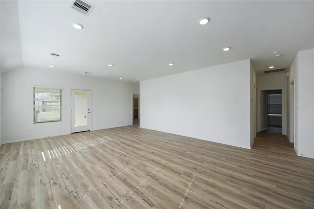 an empty room with wooden floor and natural light