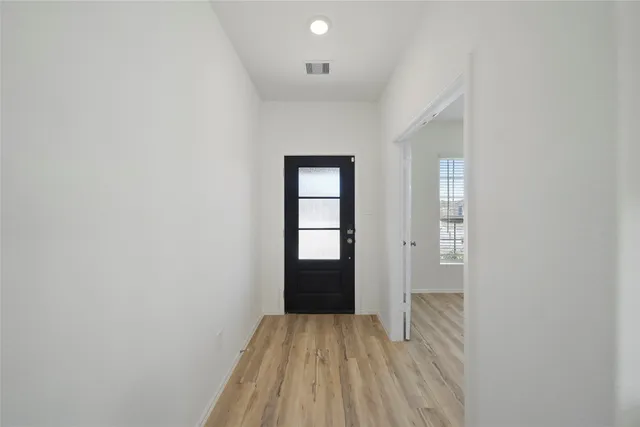 a view of an empty room with window and wooden floor