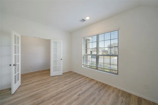 an empty room with wooden floor and windows