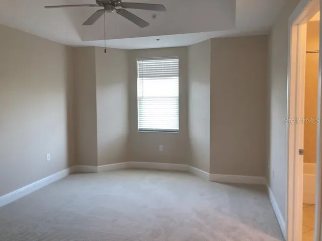 an empty room with a window and a fan