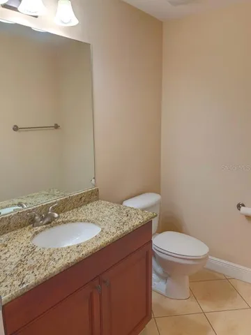a bathroom with a granite countertop sink a toilet and a mirror