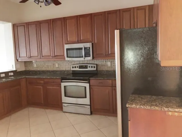 a kitchen with granite countertop a refrigerator and a stove top oven