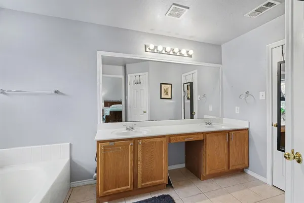 a spacious bathroom with a granite countertop sink a mirror and a bathtub